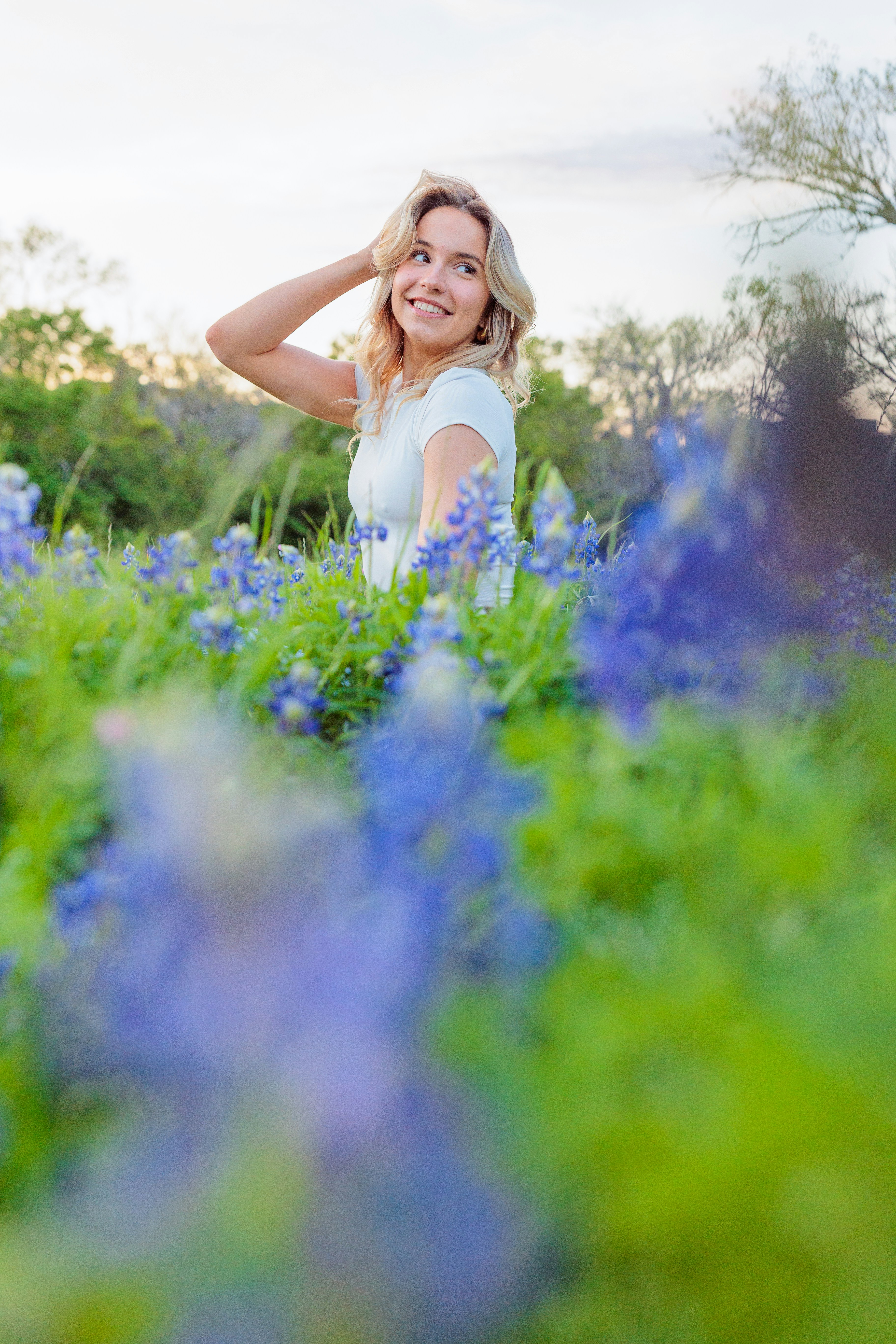 uma mulher em pé em um campo de flores azuis
