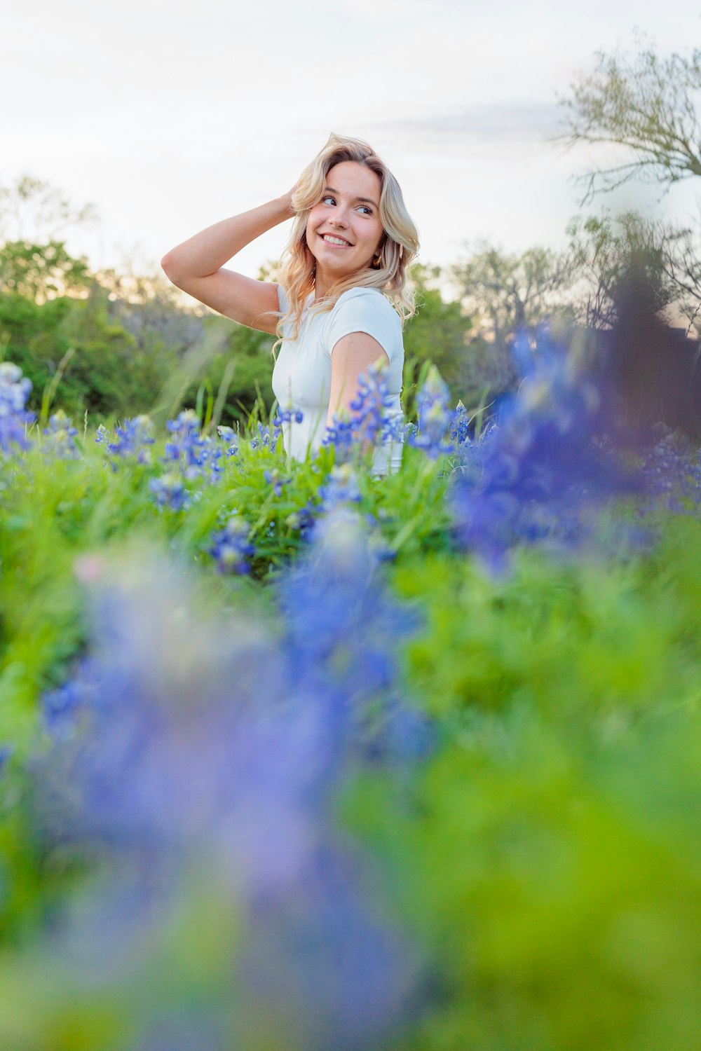 a woman standing in a field of blue flowers