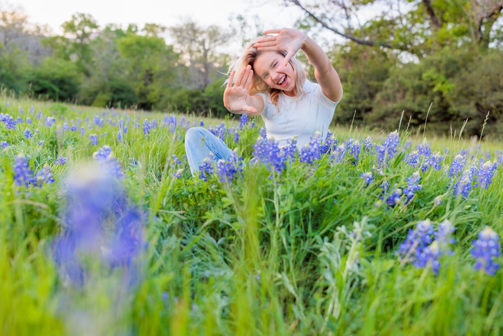 a woman sitting in a field of blue flowers