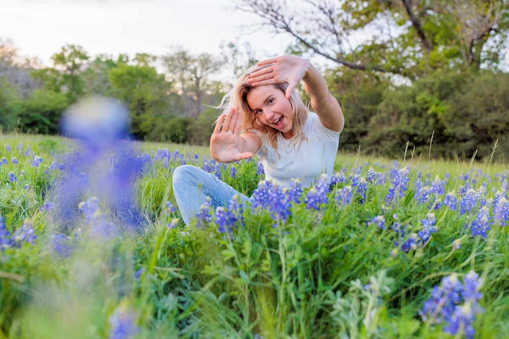 a woman sitting in a field of blue flowers