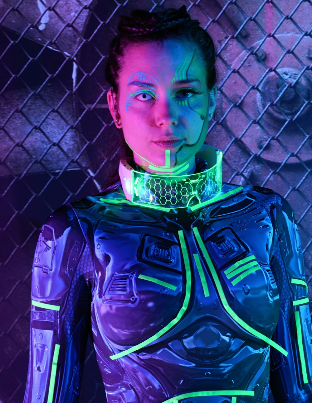 a woman in a futuristic suit standing in front of a fence