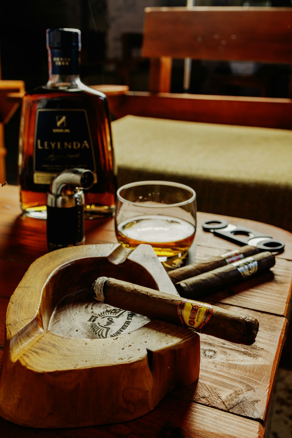 a wooden table topped with a bottle of liquor and a cigar