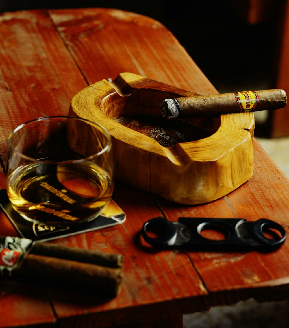 a glass of wine and a cigar on a wooden table