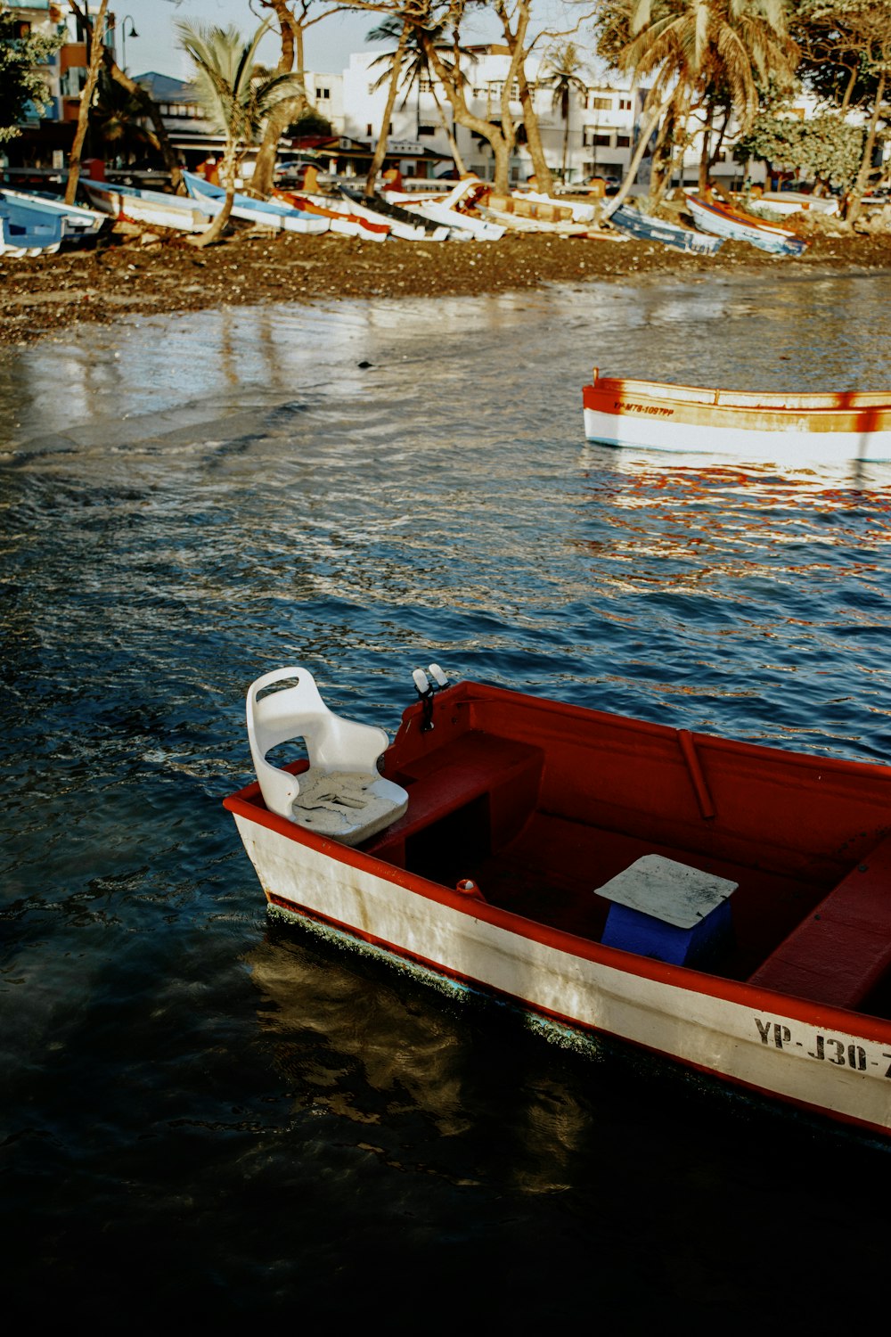 a red and white boat floating on top of a body of water