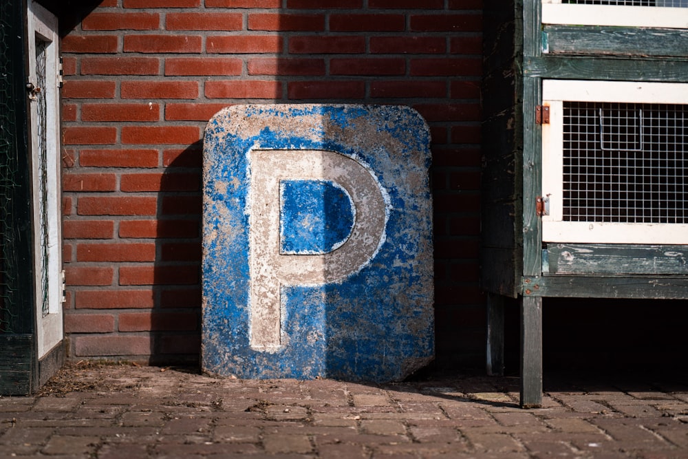 a blue parking sign sitting next to a brick wall