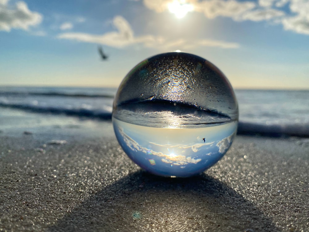 a glass ball sitting on top of a sandy beach