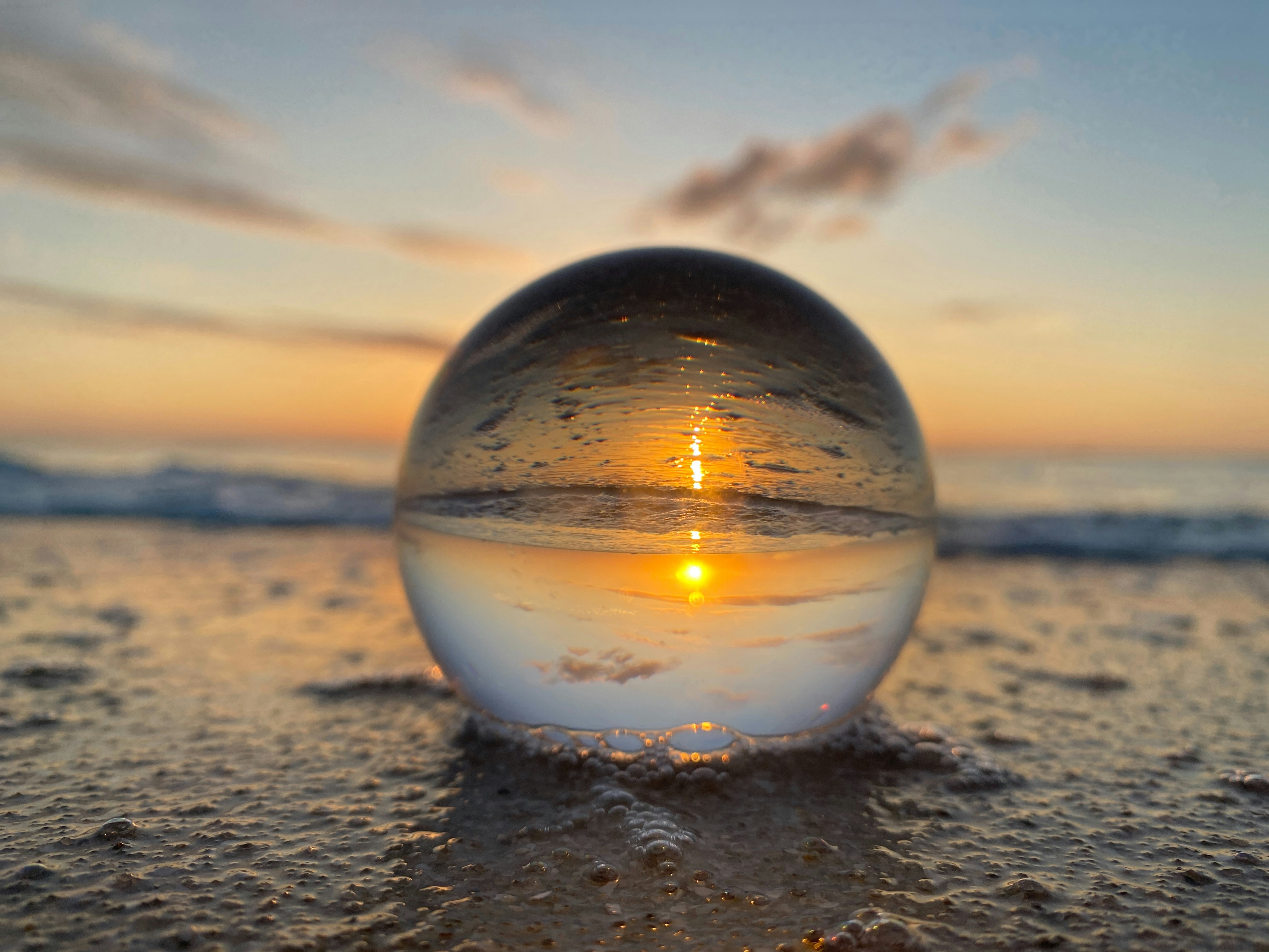 a glass ball sitting on top of a sandy beach