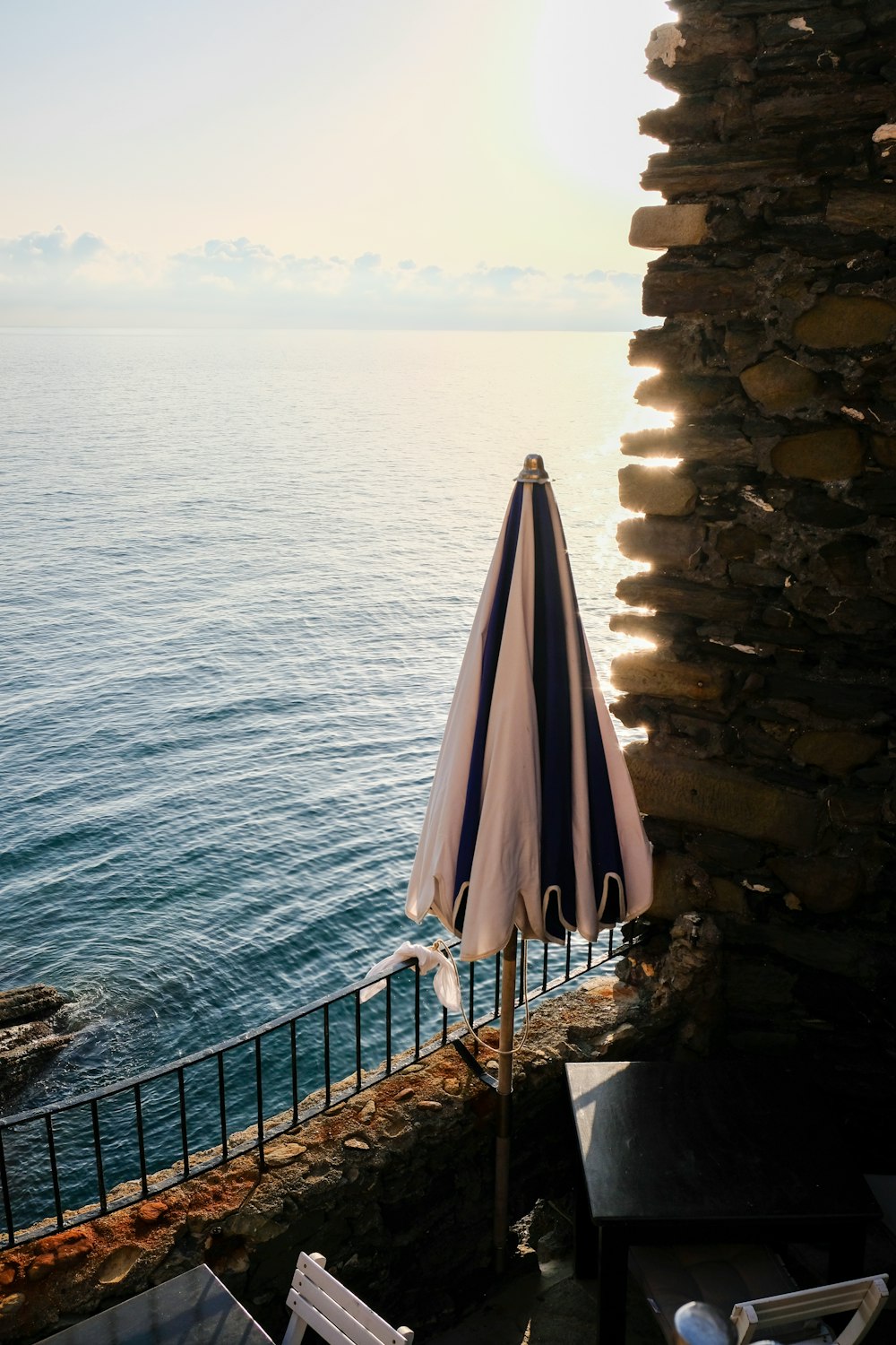 a table with an umbrella on top of it next to the ocean
