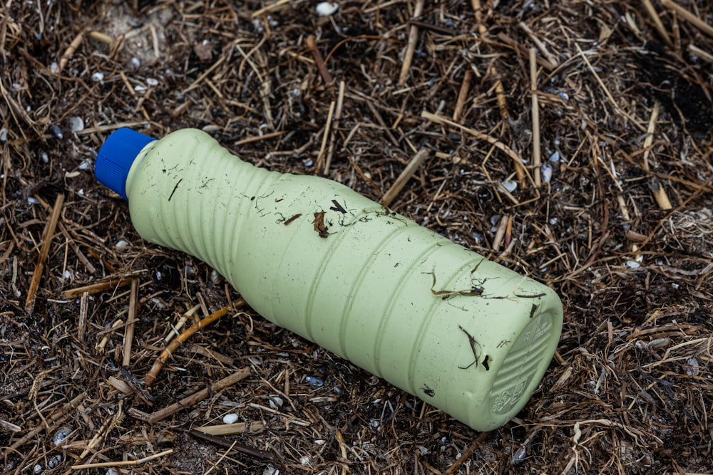 a green plastic bottle laying on the ground