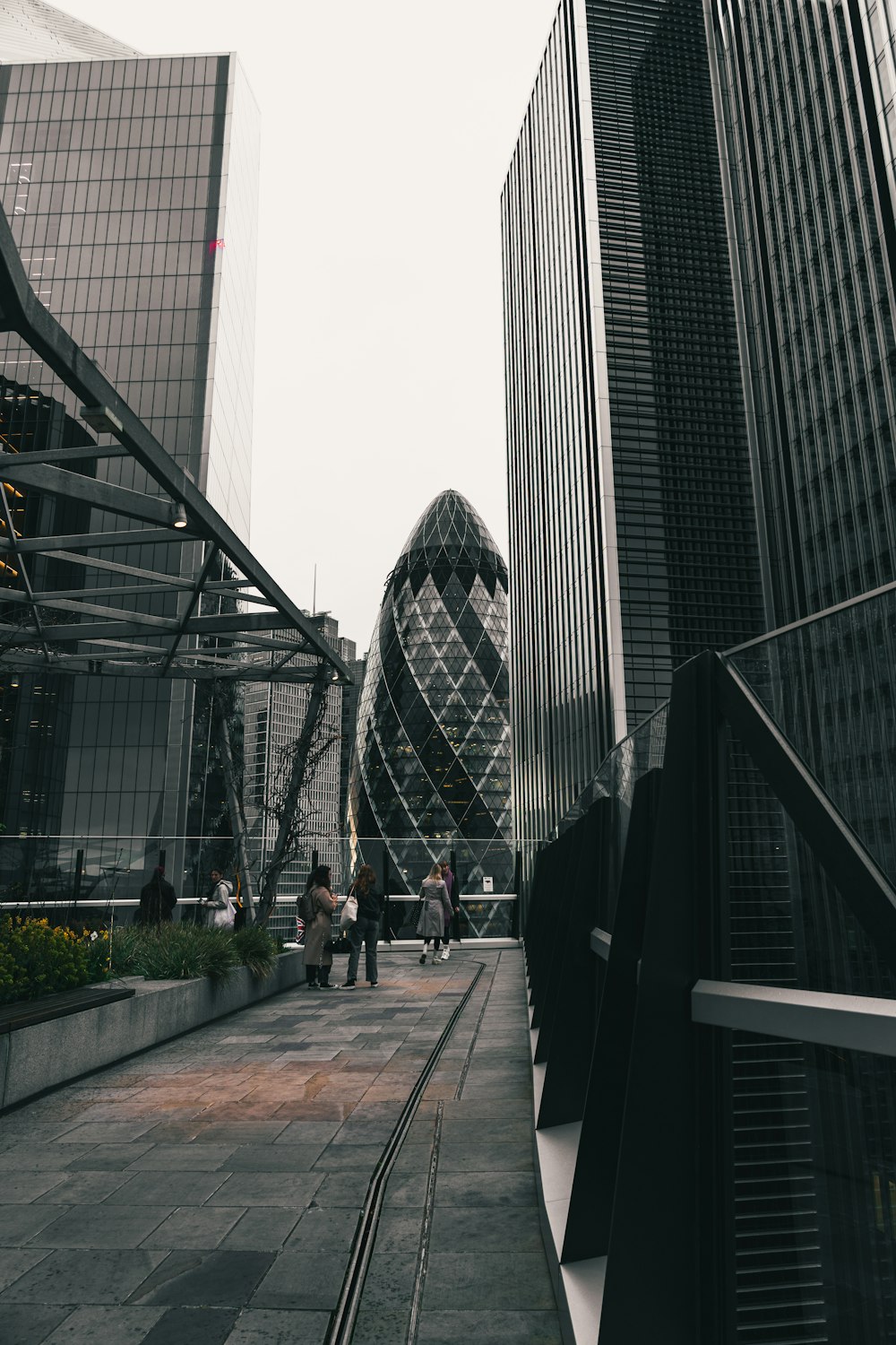 a group of people walking down a sidewalk next to tall buildings