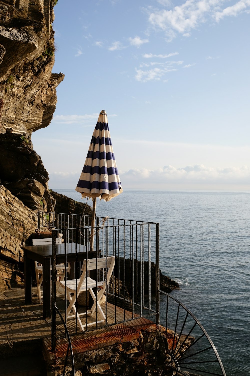 a table and umbrella on a balcony overlooking the ocean