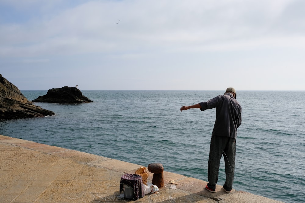 a man pointing at the ocean while two children sit on the edge of a pier