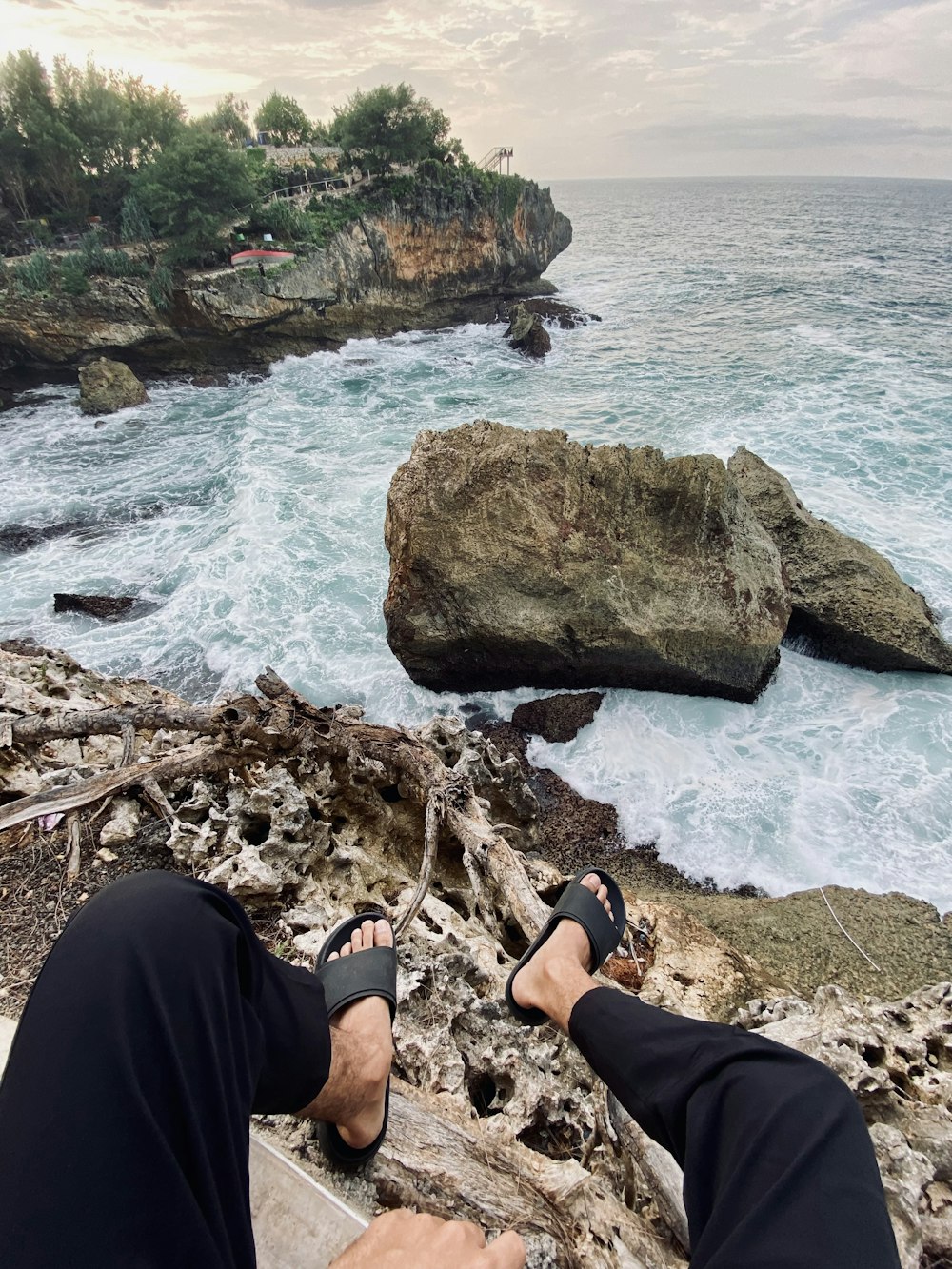 a man is sitting on a rock near the ocean