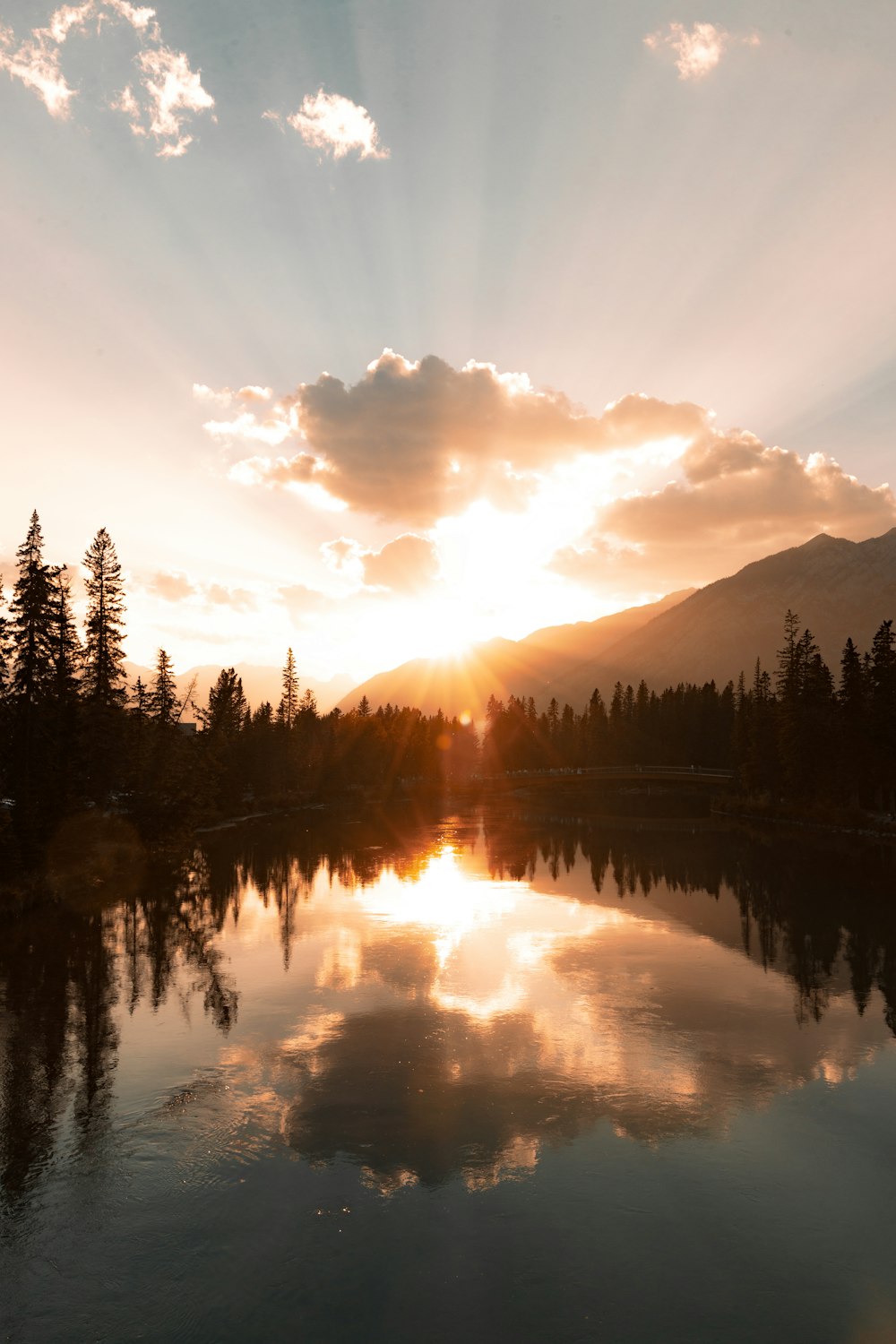 the sun is setting over a lake with a mountain in the background