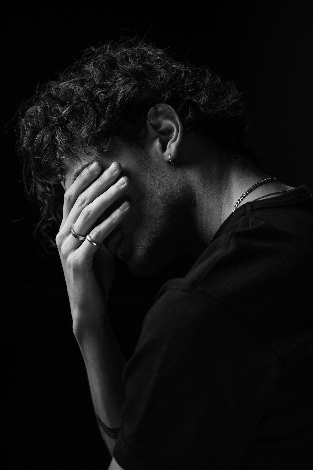 a black and white photo of a man covering his face