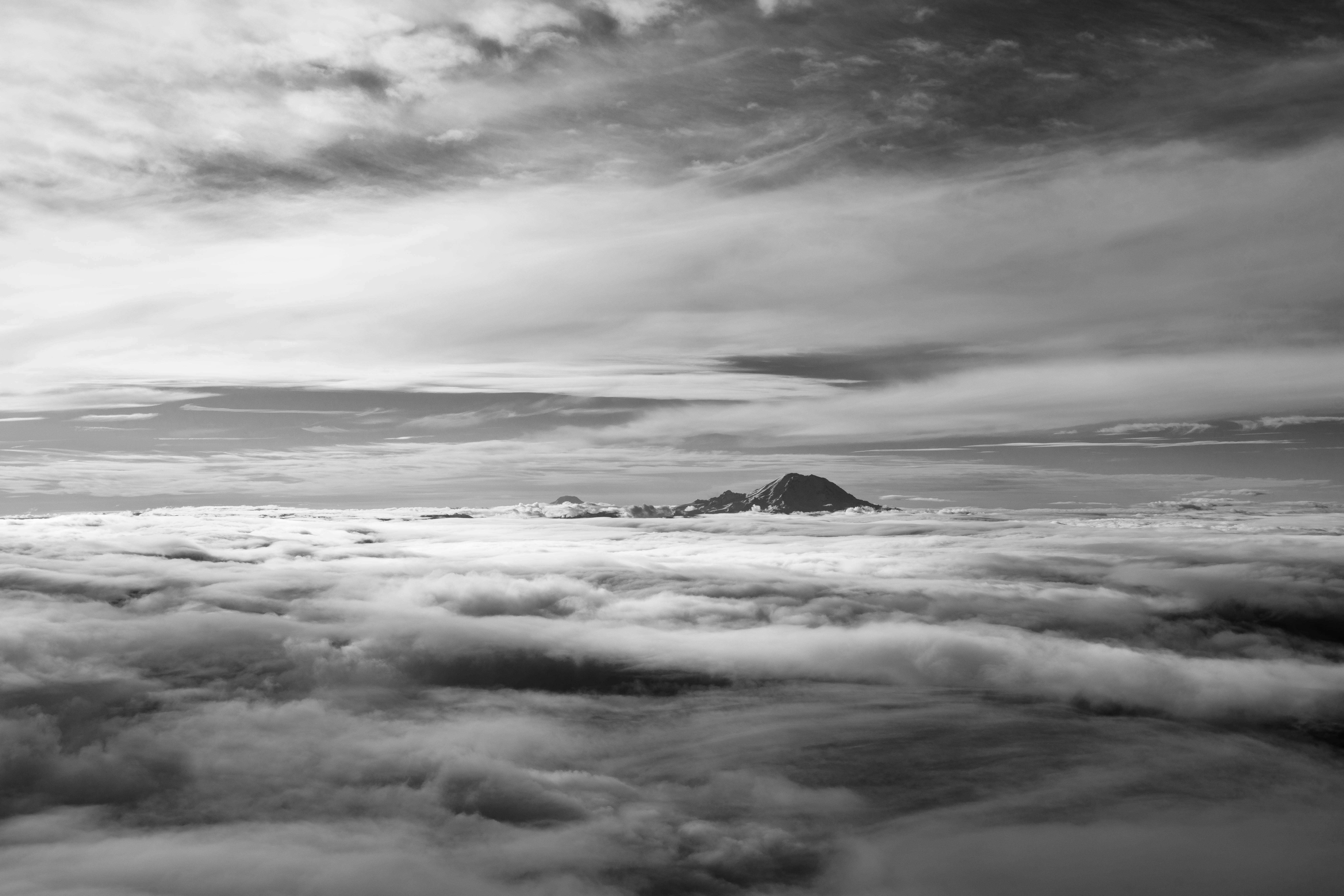 une photo en noir et blanc de nuages et d’une montagne