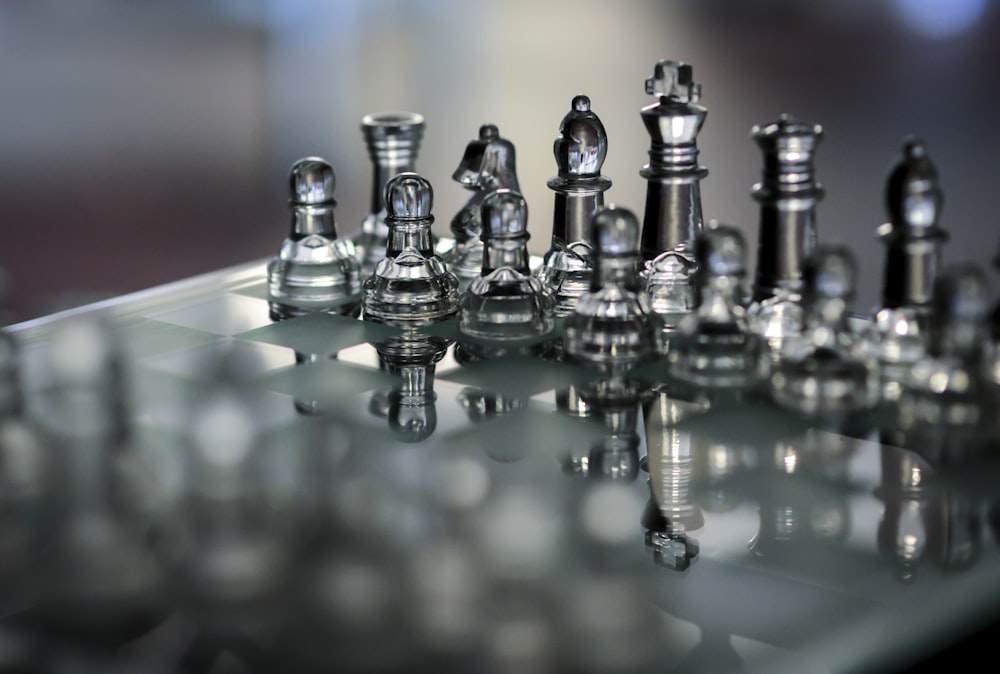 a glass chess board with silver chess pieces