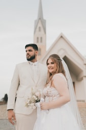 a bride and groom standing in front of a church