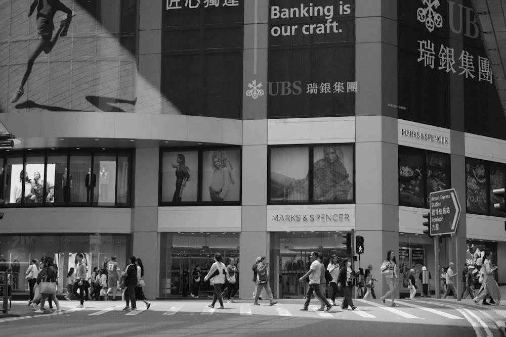 a group of people crossing a street in front of a bank