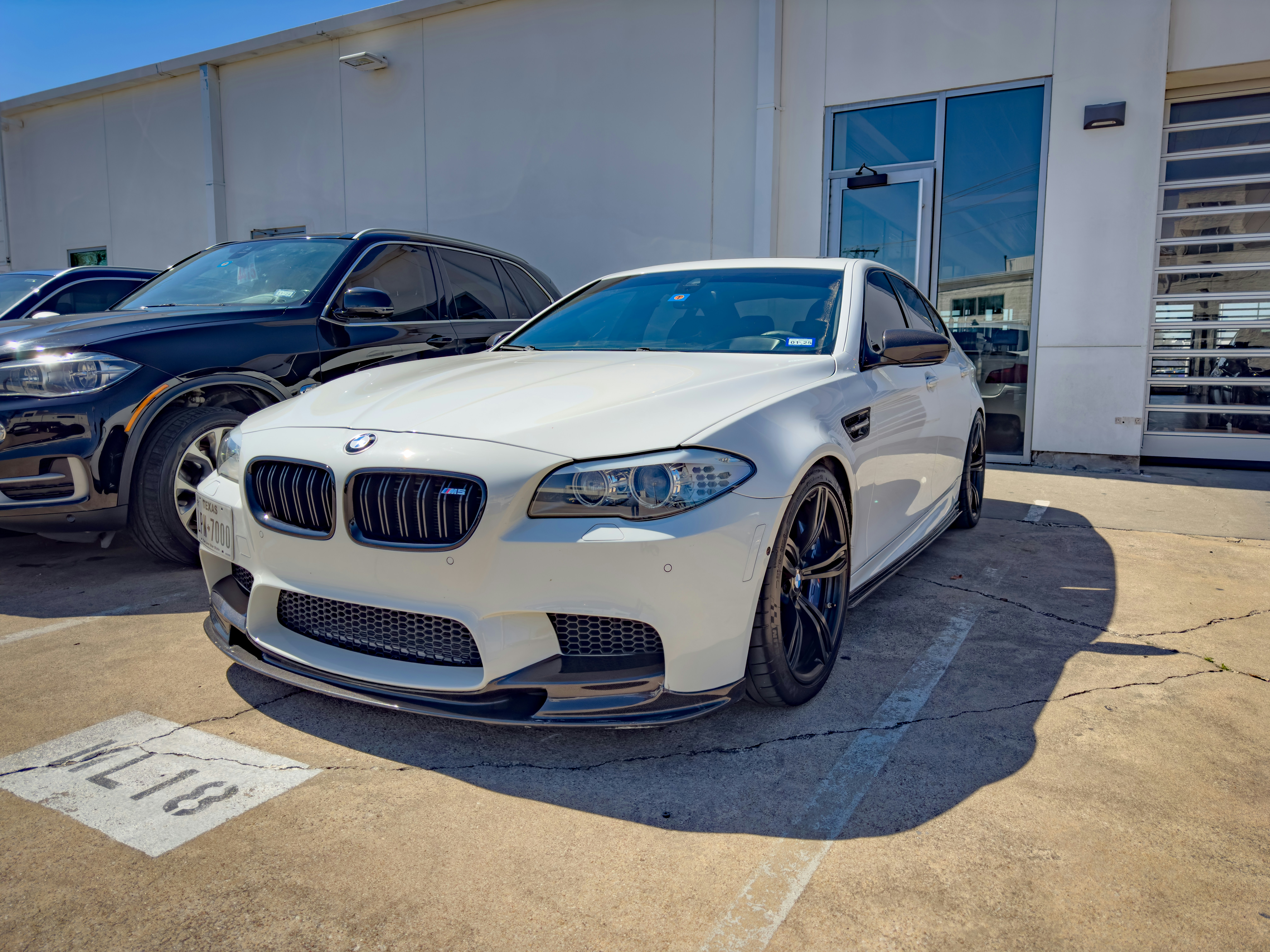 White BMW 5 Series sedan on a boulevard, sleek aerodynamic body with signature kidney grille and premium finish