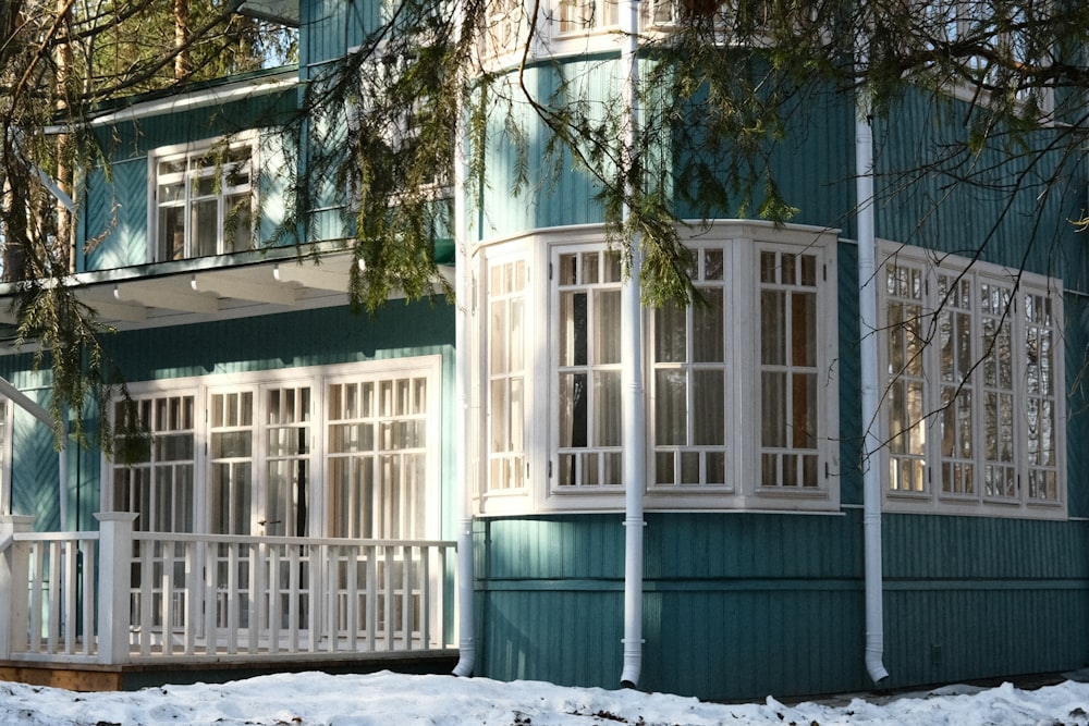 a blue building with white windows and a snow covered ground