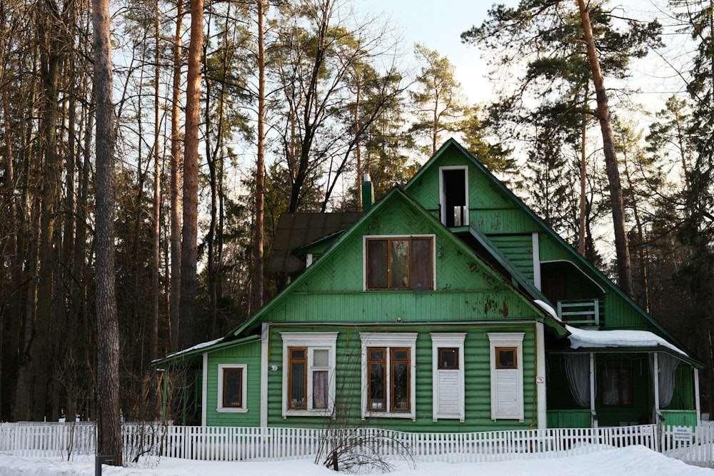 a green house with a white picket fence