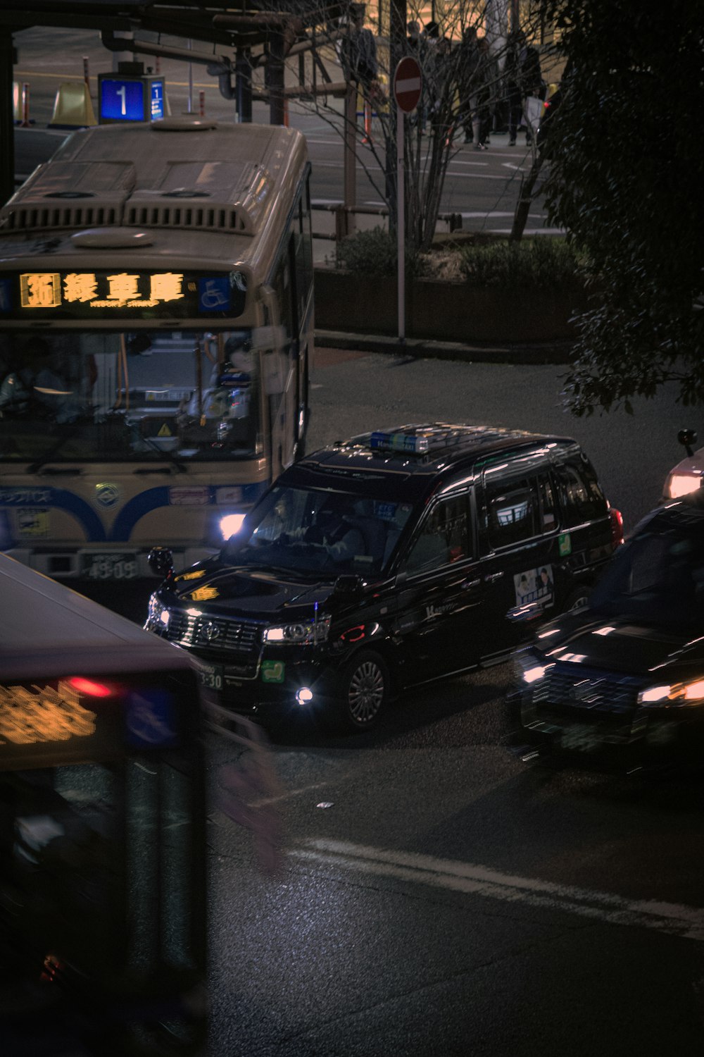 a city street at night with cars and a bus