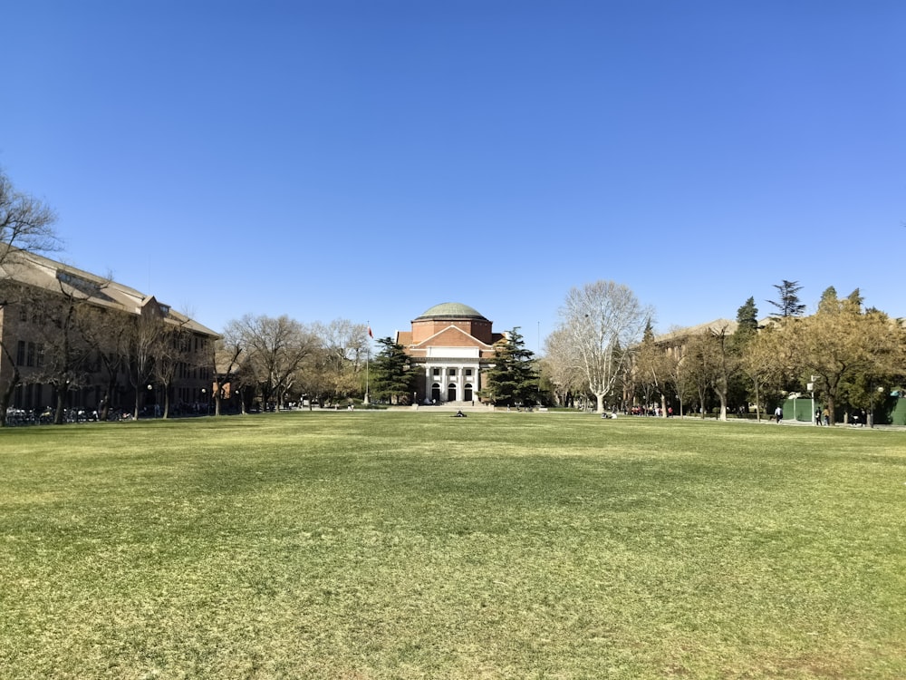 a large grassy field with a building in the background