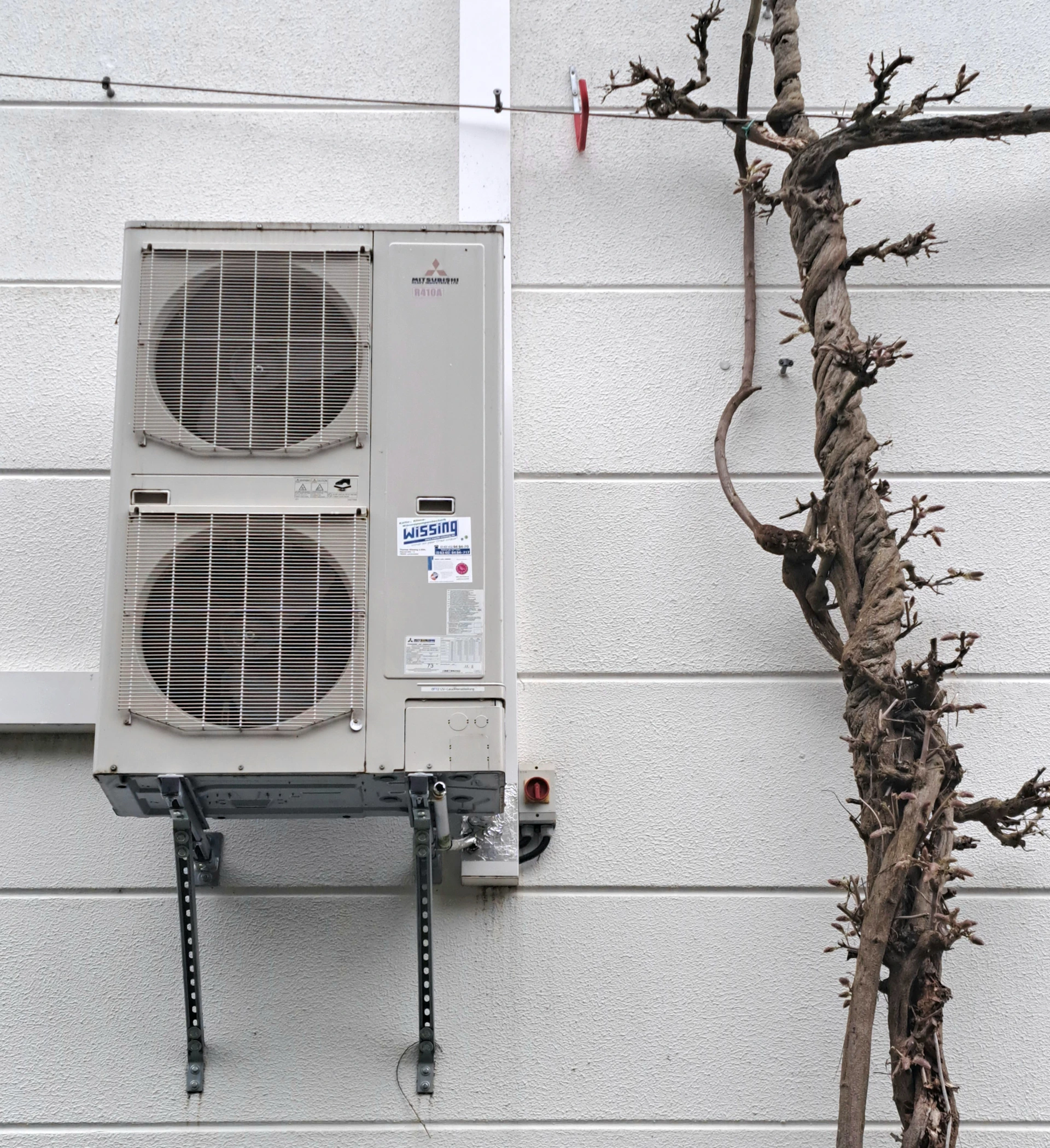 a wall mounted air conditioner next to a tree