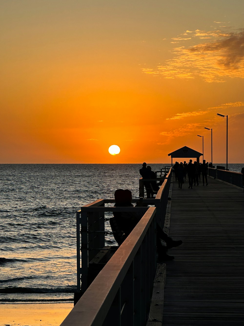 a person sitting on a pier watching the sun set