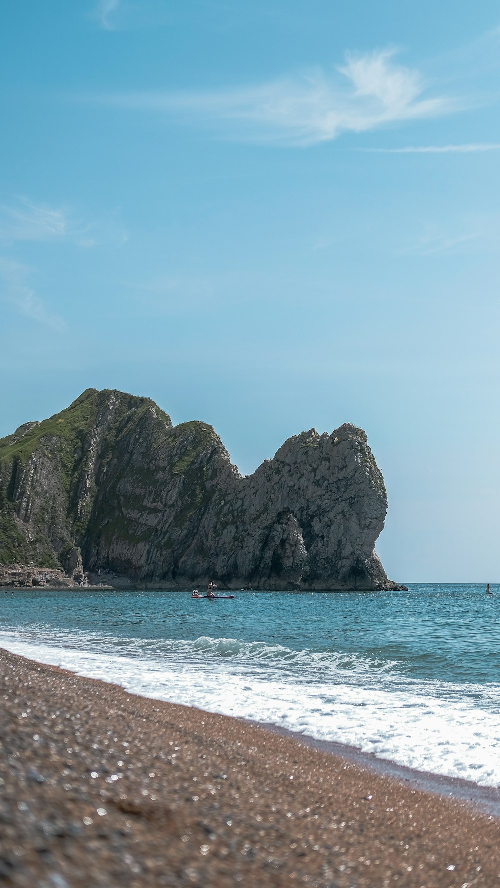 a rocky outcropping in the ocean next to a beach