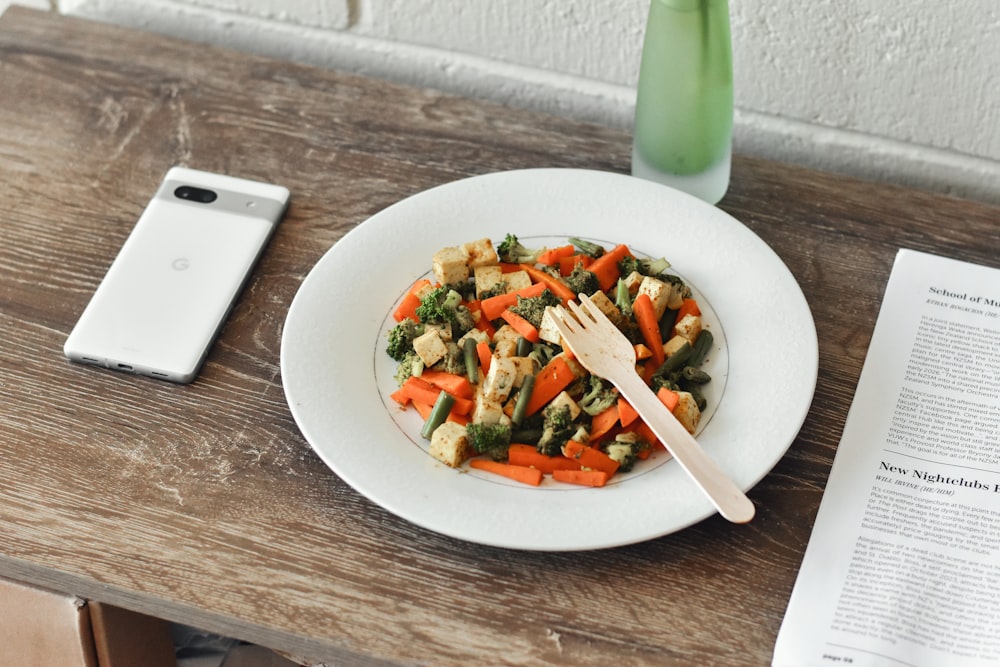 a plate of food on a table next to a cell phone