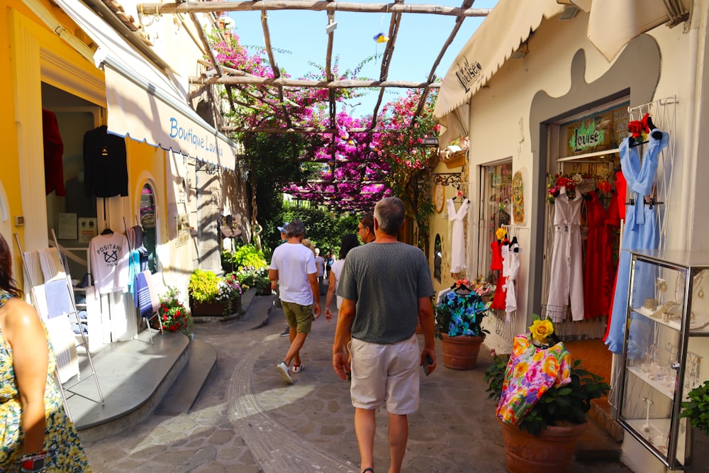 Un grupo de personas caminando por una calle al lado de una tienda