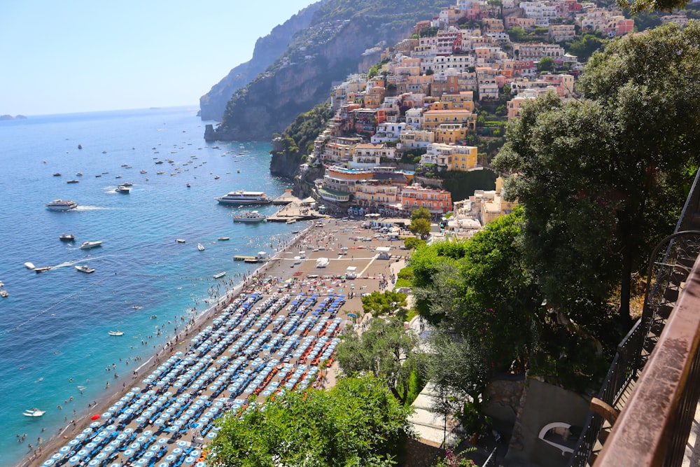 a beach filled with lots of boats next to a hillside