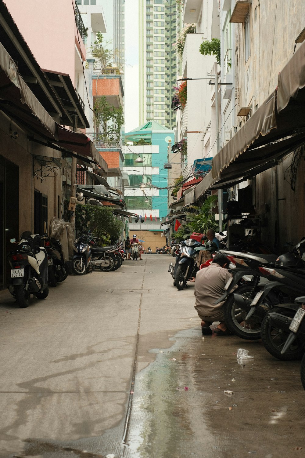 a narrow city street lined with parked motorcycles