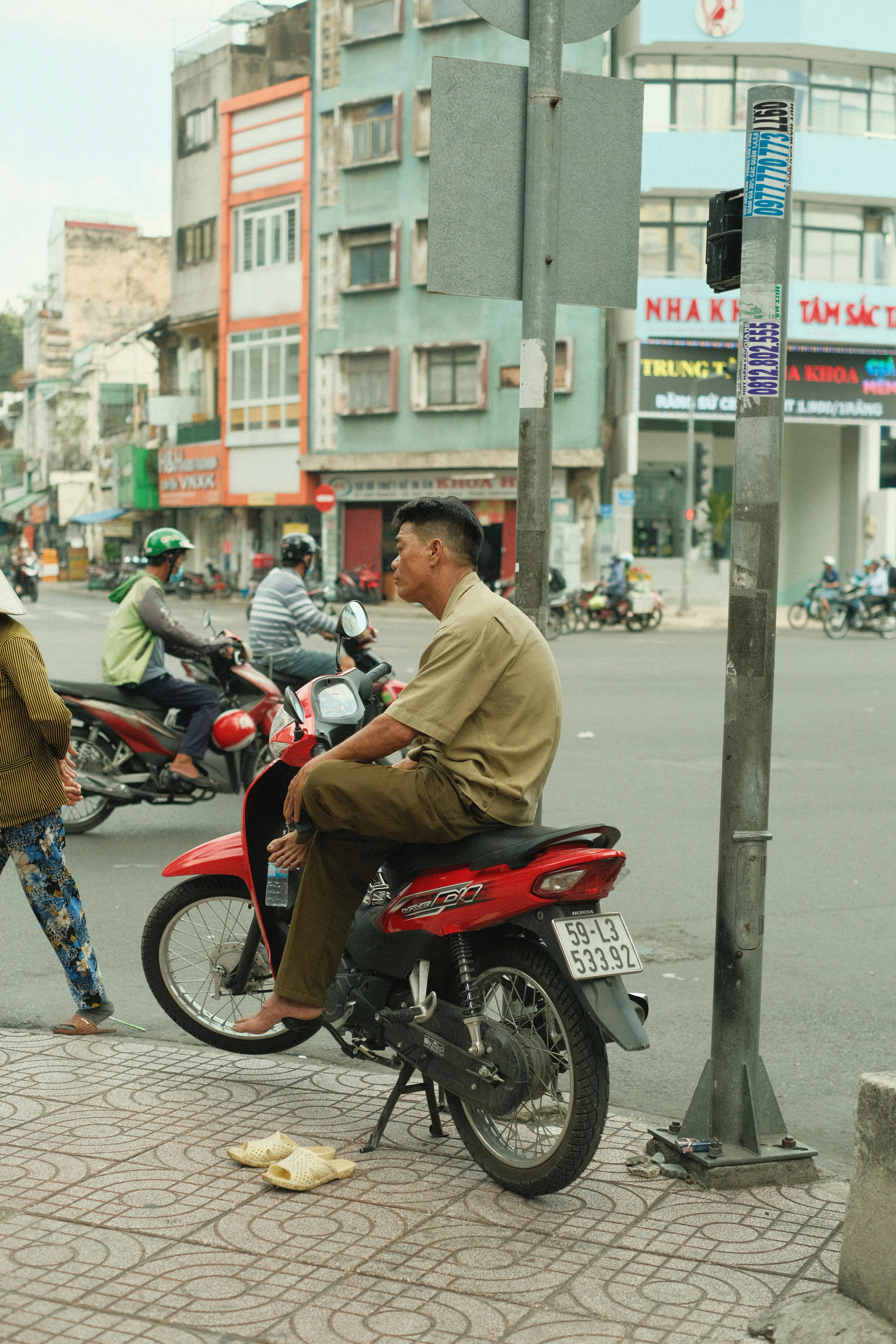 A man riding a red motorcycle down a street