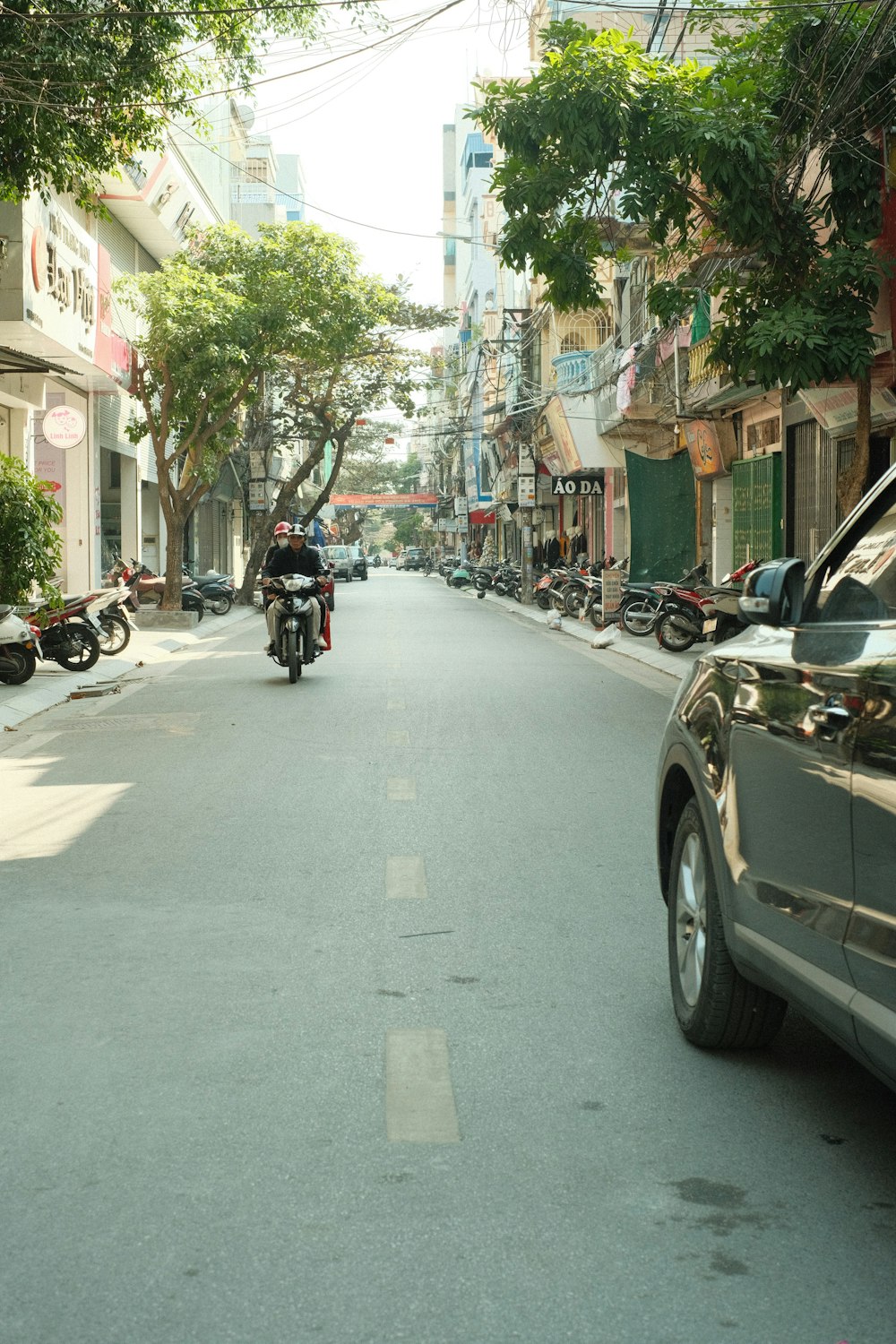 a motorcyclist rides down a street lined with parked cars
