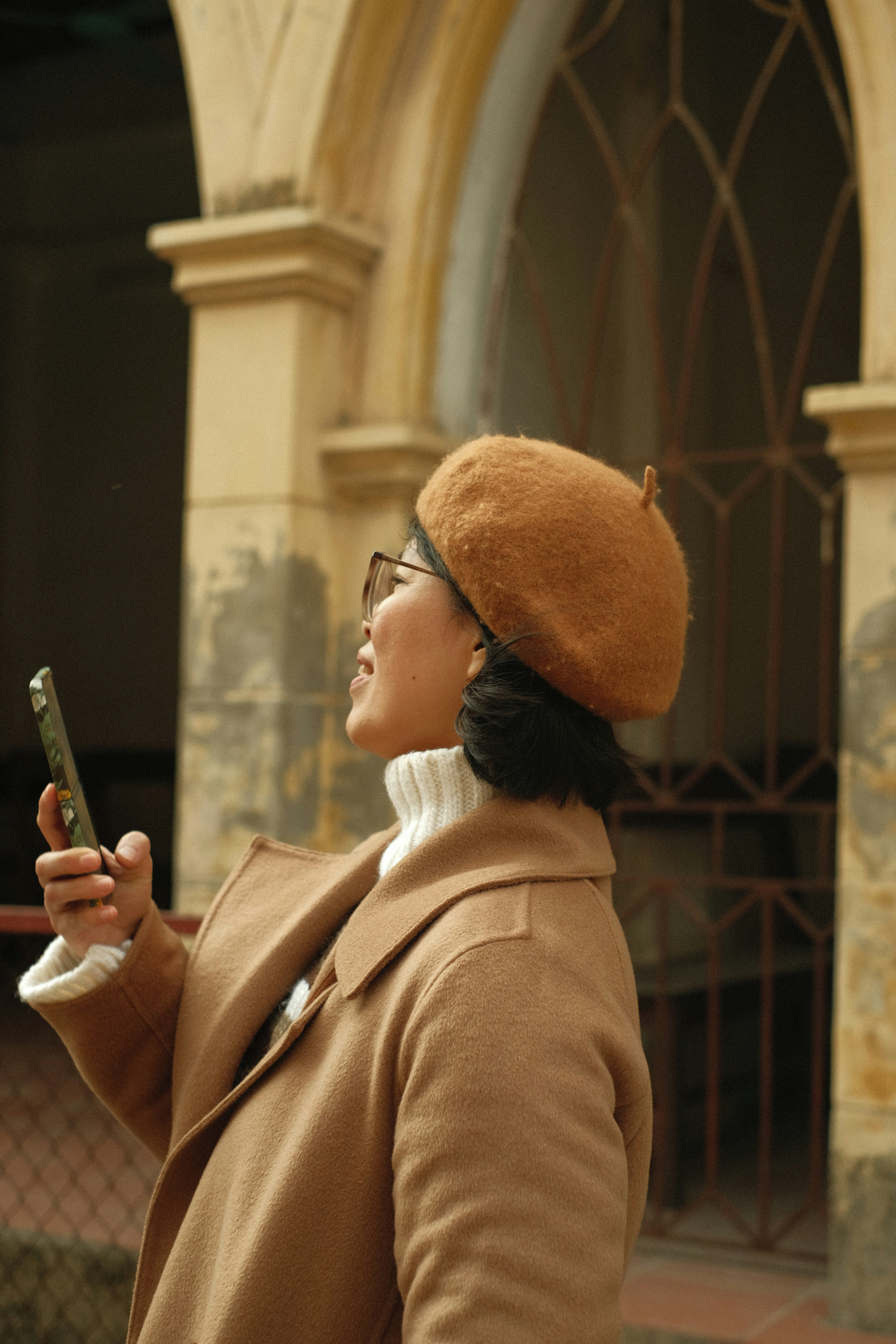 A woman in a brown coat and a brown hat looking at her cell phone