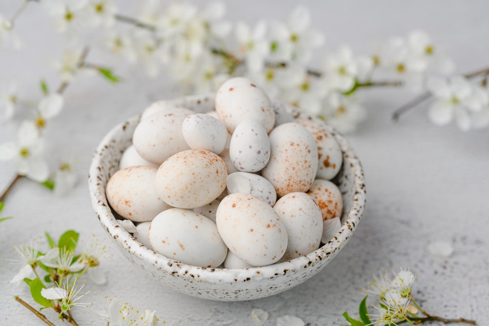 uma tigela cheia de ovos salpicados brancos e marrons