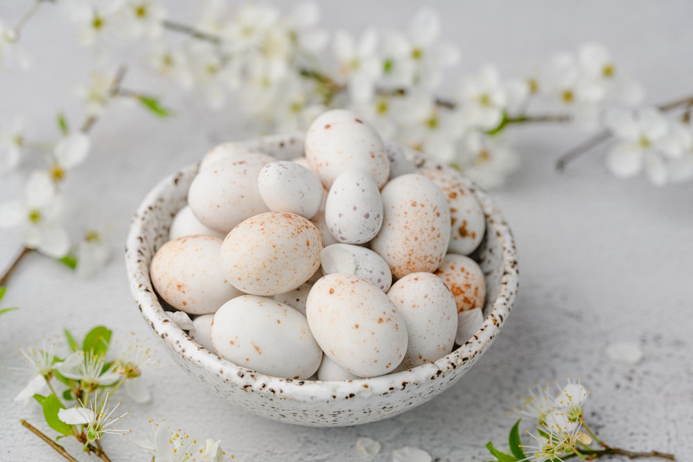 a bowl filled with white and brown speckled eggs