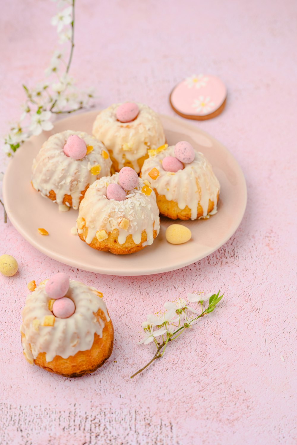 a plate of cookies with white frosting and pink candies