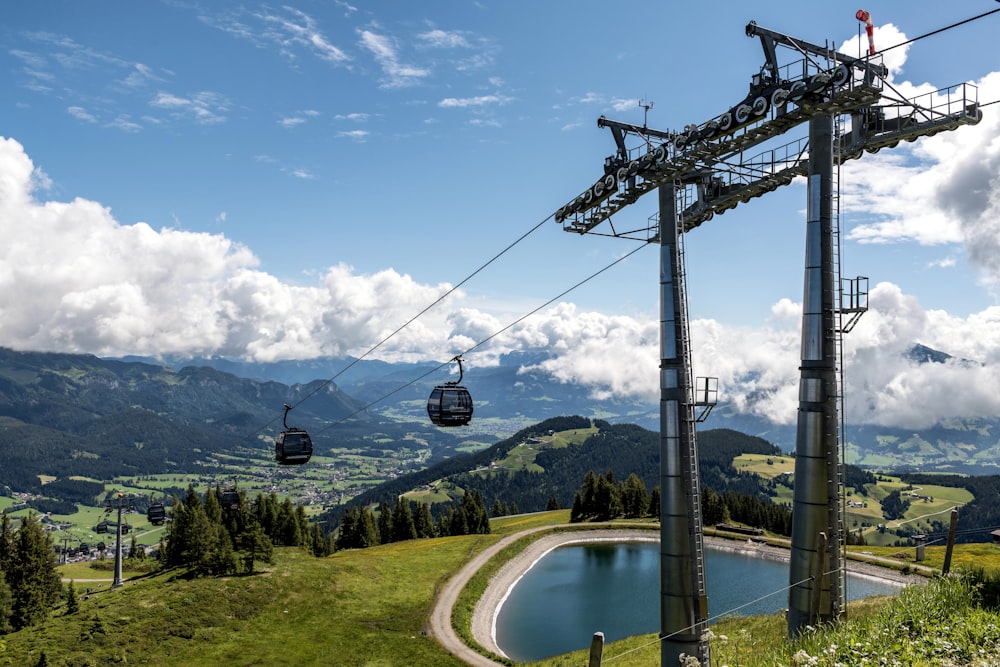 a couple of gondola lifts above a lake in the mountains