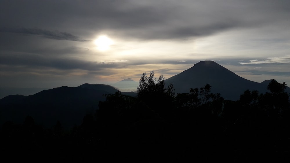 the sun shines through the clouds over a mountain