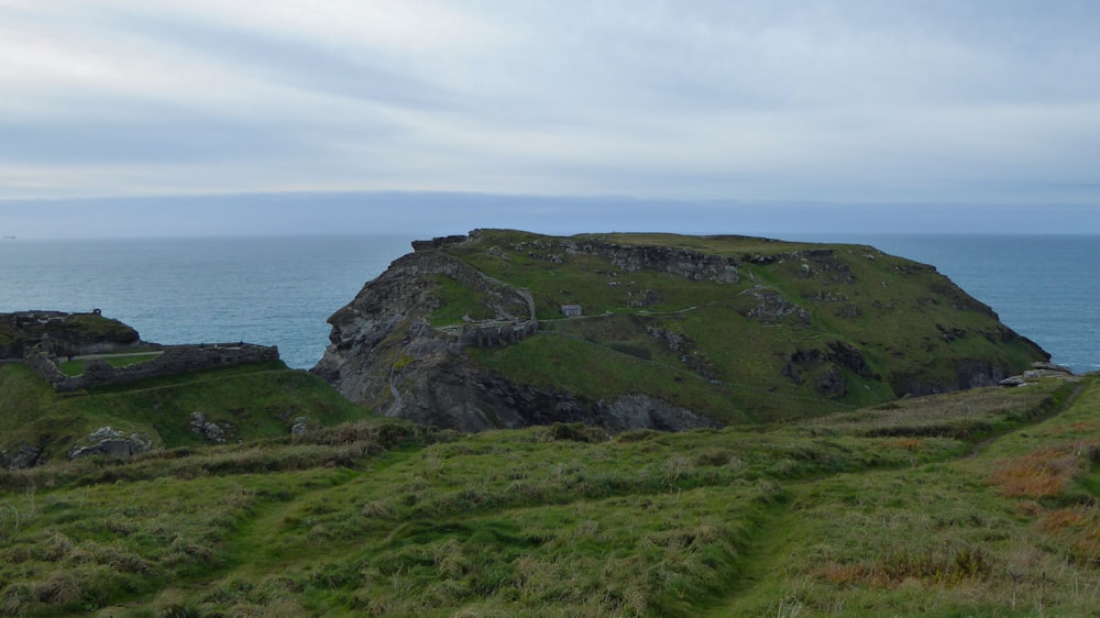 a grassy hill with a large rock outcropping