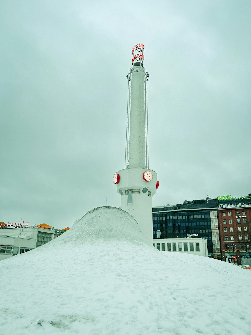 a large mound of snow with a clock tower in the background