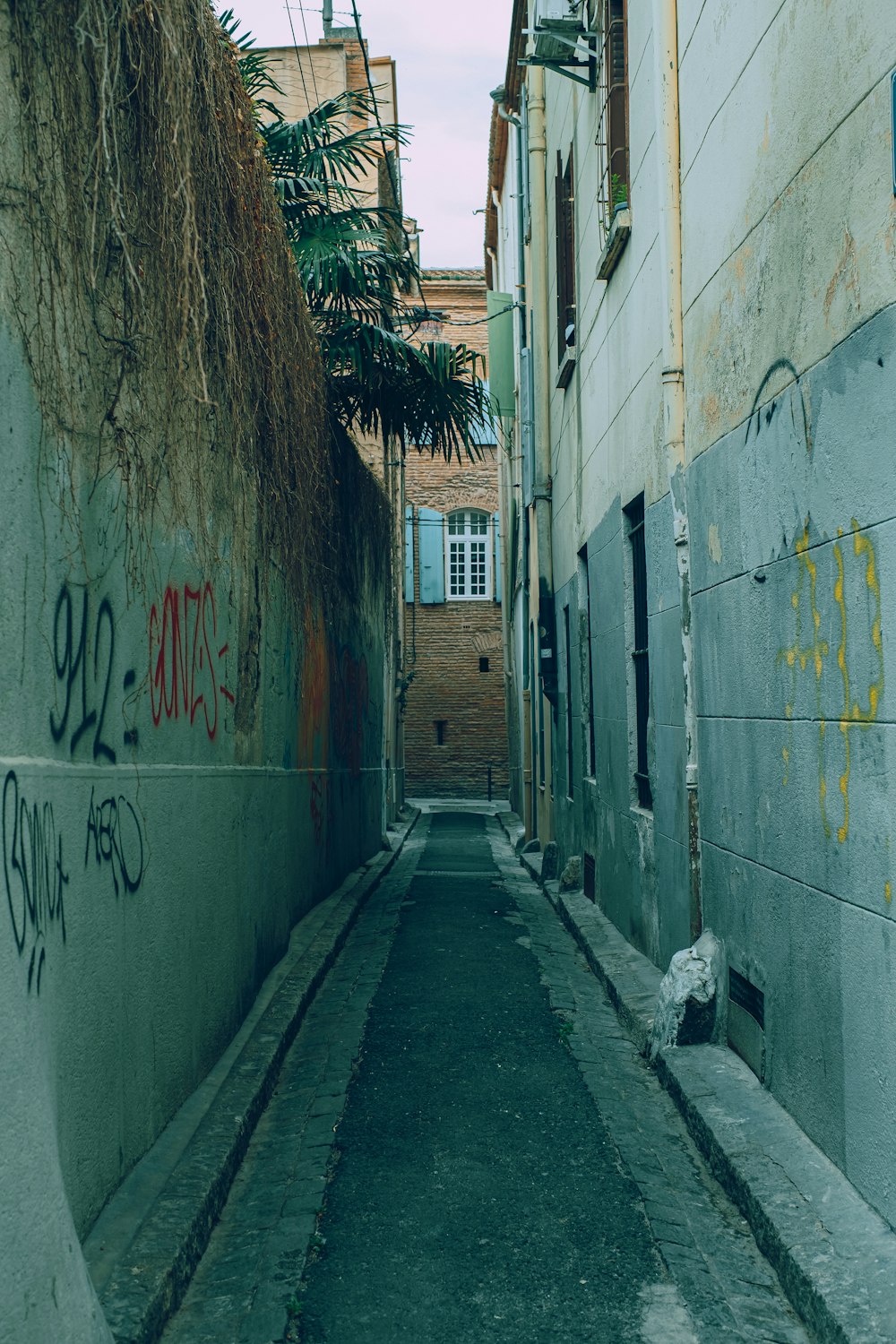 a narrow alley with graffiti on the walls