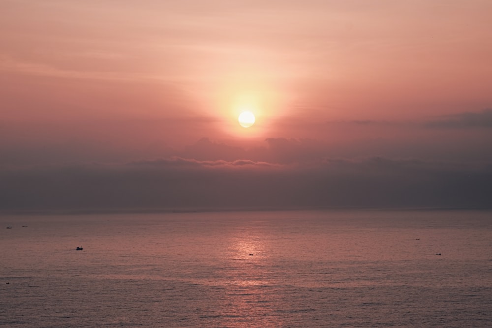 a large body of water with a sunset in the background