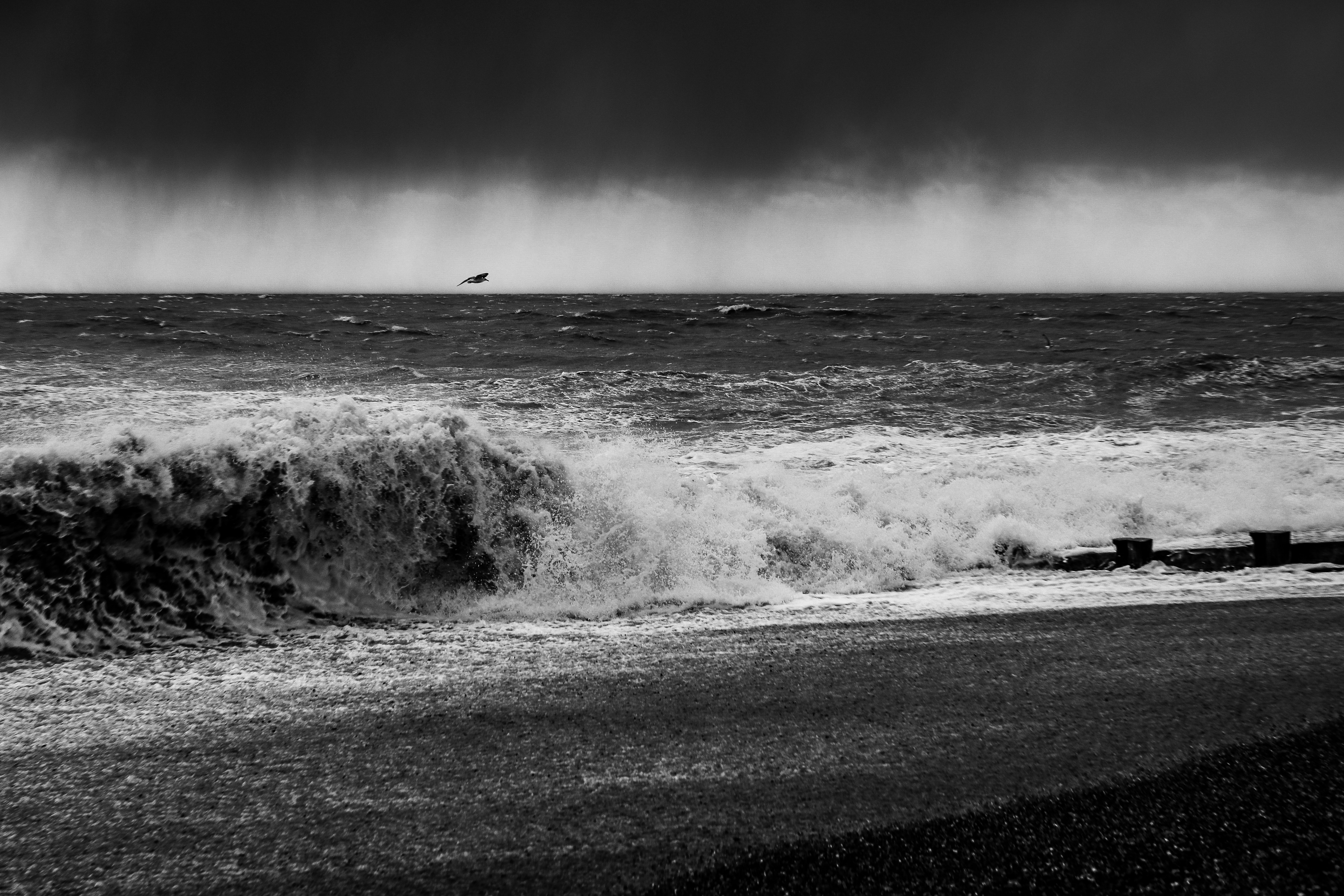 a black and white photo of the ocean with a boat in the distance