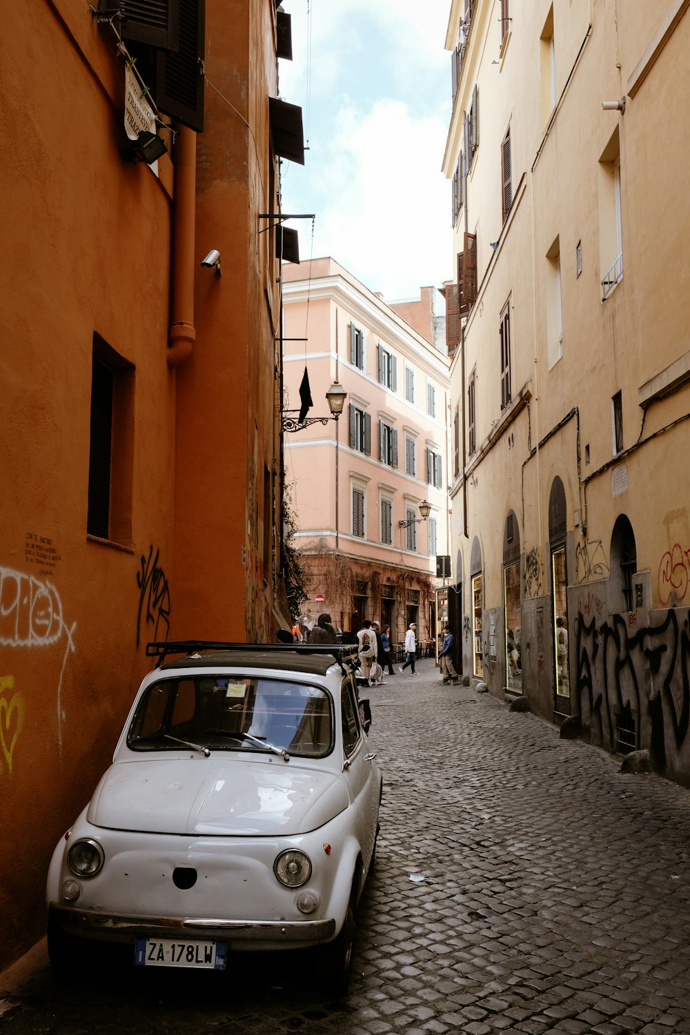 a small white car parked on a cobblestone street