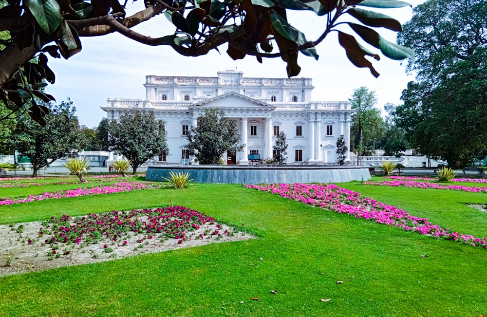 a large white building sitting on top of a lush green field